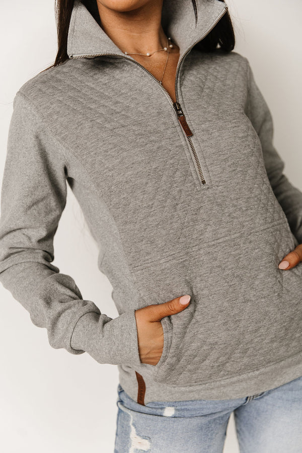 Person wearing a gray zip-up hoodie with a neutral background